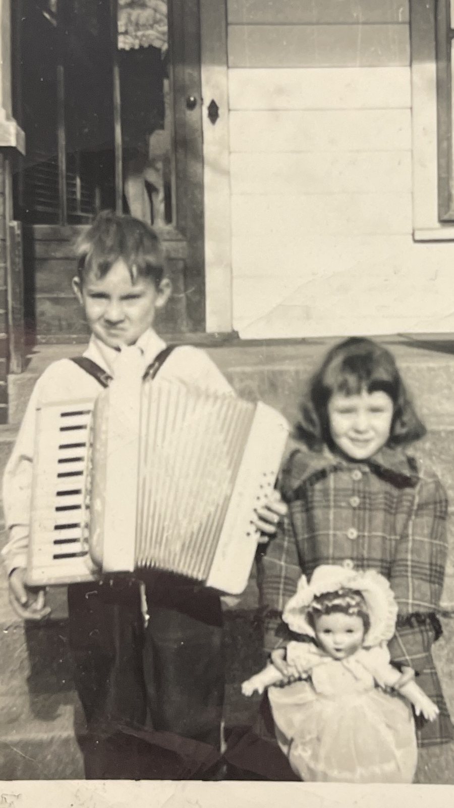 Joseph as a boy holding an accordion, his sister beside him