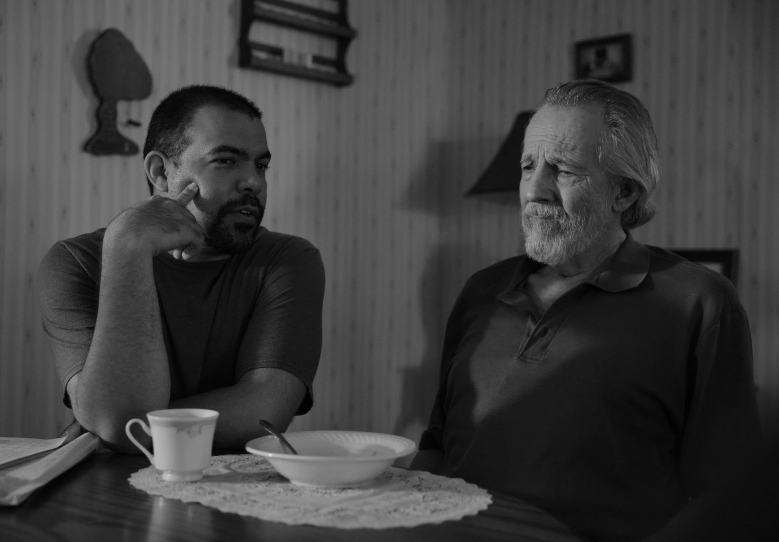 Joseph in a black and white scene at a kitchen table